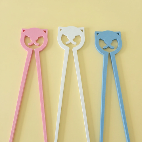 Three 3D printed cat training chopsticks in pastel pink, white, and blue